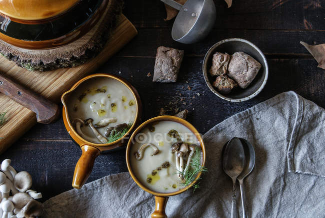Served in bowls tasty mushroom cream on rustic wooden table with ingredients — Stock Photo