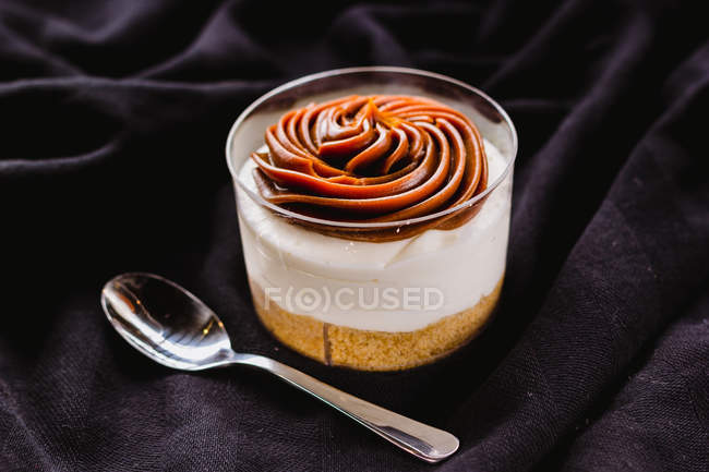 Sobremesa em xícara com mousse de caramelo em tecido preto — Fotografia de Stock