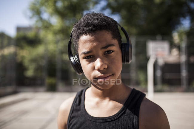 Афро молодий хлопчик слухає музику з навушниками на баскетбольному майданчику — стокове фото