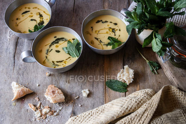 Corn cream soup with coconut and pesto in bowls on wooden table — Stock Photo