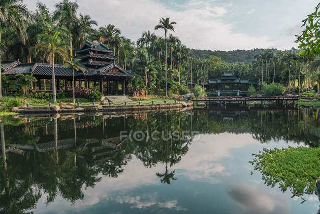 Paysage du lac tranquille dans un parc exotique avec des bâtiments orientaux traditionnels sur fond, Nanning, Chine — Photo de stock