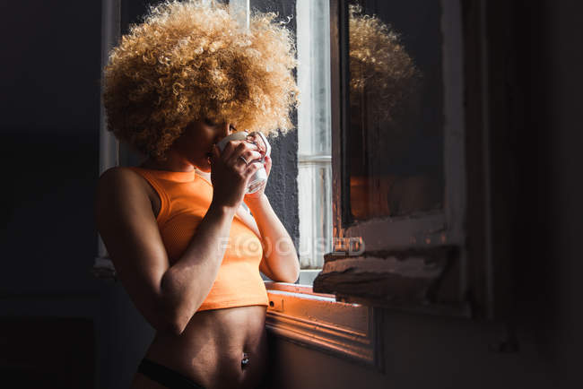 Schlanke Frau in Unterwäsche steht mit Tasse am Fenster — Stockfoto