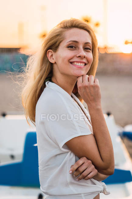Porträt einer glücklichen blonden Frau, die bei Sonnenuntergang am Strand posiert — Stockfoto
