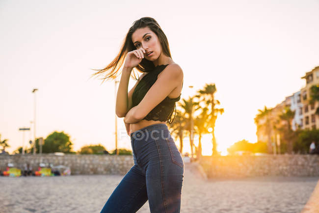 Gorgeous brunette woman posing on beach at sunset — Stock Photo