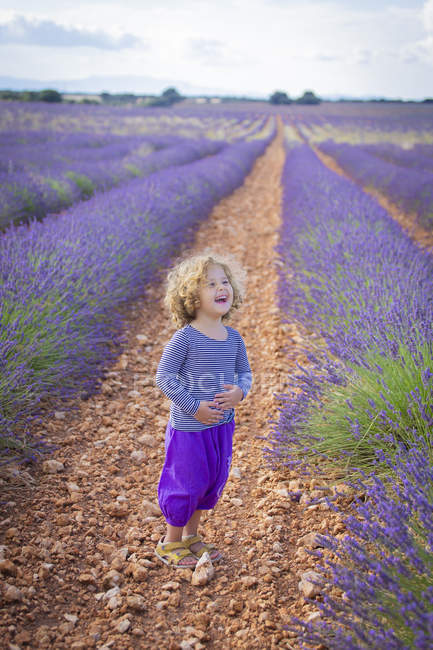 Сміється маленька дівчинка стоїть у фіолетовому лавандовому полі — стокове фото