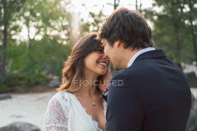 Glücklicher erwachsener Mann mit schöner Braut, die einander im Sonnenlicht im Freien anschaut und streichelt — Stockfoto