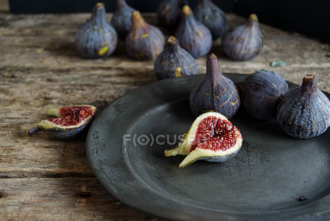 Figos maduros brilhantes na placa na superfície de madeira — Fotografia de Stock