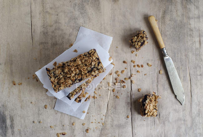 Homemade stacked granola bars on baking parchment on wooden surface — Stock Photo