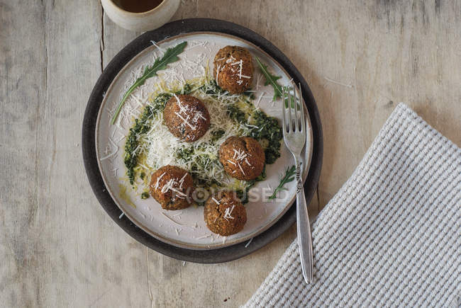 Polpette di lenticchie guarnite con salsa di pesto rucola e formaggio sul piatto sul tavolo di legno — Foto stock