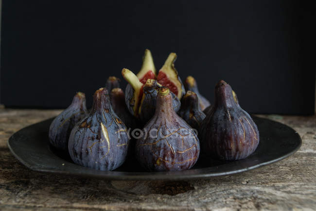 Bright ripe figs on plate on wooden surface — Stock Photo
