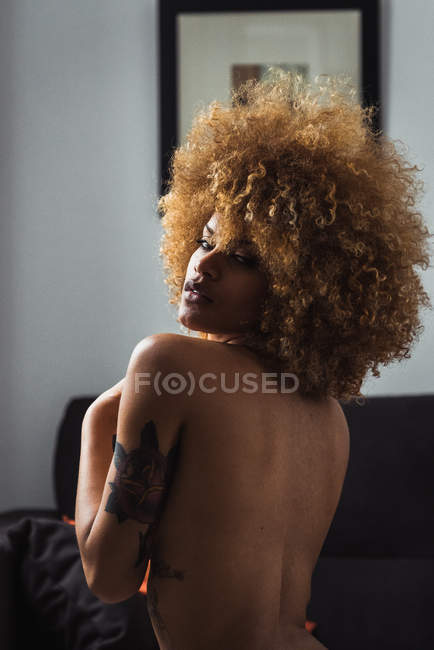 Étnica mujer en topless mirando provocativamente a la cámara - foto de stock