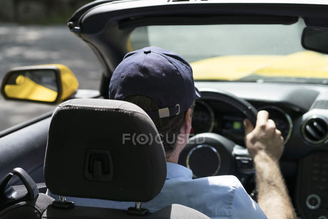 Homem em cap dirigindo cabriolet na rua — Fotografia de Stock