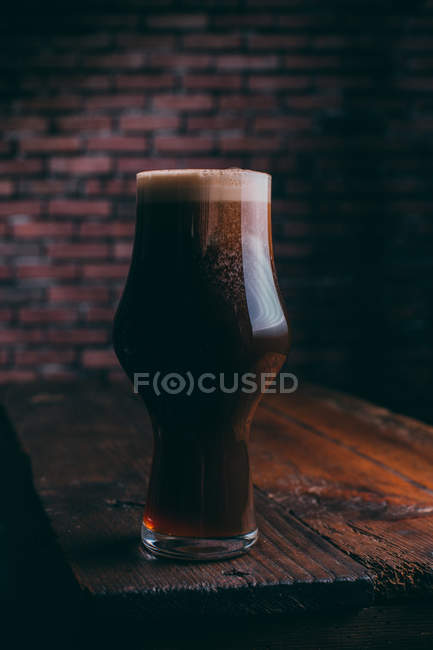 Stout beer in glass on wooden table on dark background — Stock Photo