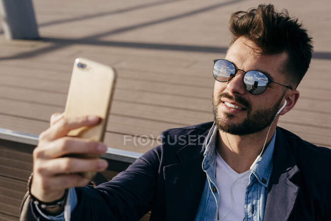 Stylish man relaxing with music on seafront — Stock Photo