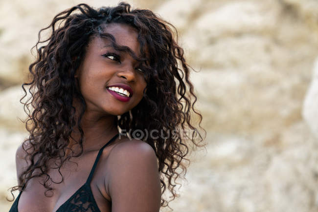 Affascinante donna nera in pizzo superiore guardando lontano contro scogliera — Foto stock