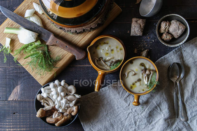 Servi dans des bols savoureux crème de champignons sur une table en bois rustique avec des ingrédients — Photo de stock