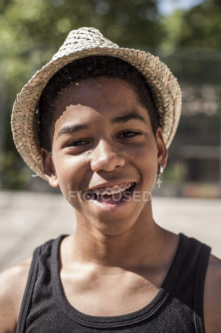 Портрет молодого хлопчика в солом'яному капелюсі, що стоїть на відкритому повітрі і дивиться на камеру — стокове фото