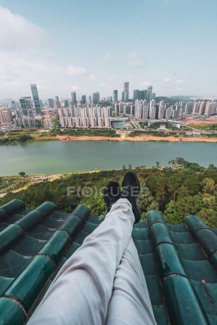 Piernas de turista en la azotea con paisaje urbano en el fondo, Nanning, China - foto de stock