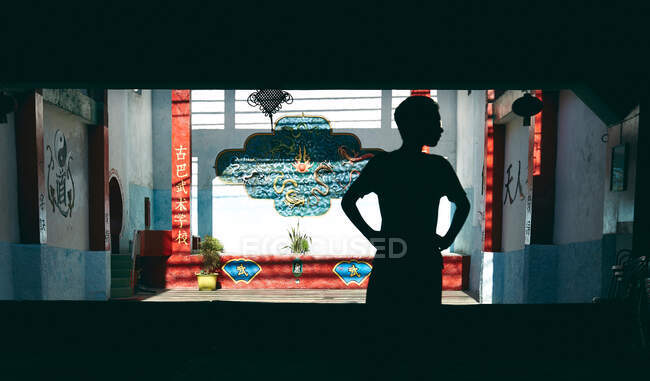 Силуэт мальчика, стоящего в тени против яркого красочного восточного дизайна патио в солнечном свете — стоковое фото