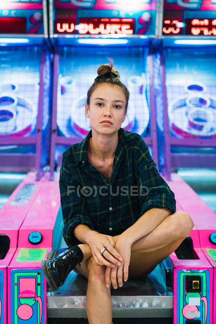 Женщина сидит посреди игровых автоматов и смотрит в камеру — стоковое фото