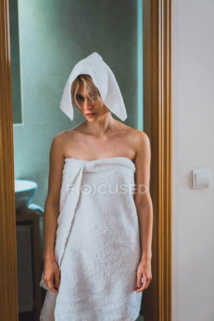 Young woman standing in bathroom doorway with towel on hair — Stock Photo