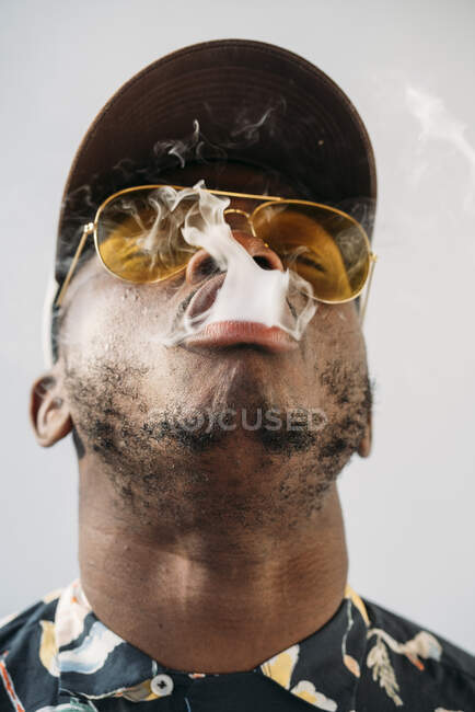 Homme élégant noir portant des lunettes de soleil. Il vapotage avec une cigarrete électronique en plein air — Photo de stock