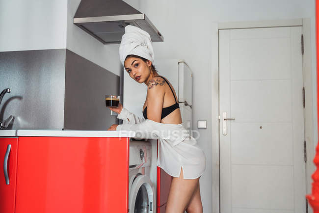 Чуттєва жінка після душу п'є каву на кухні — стокове фото