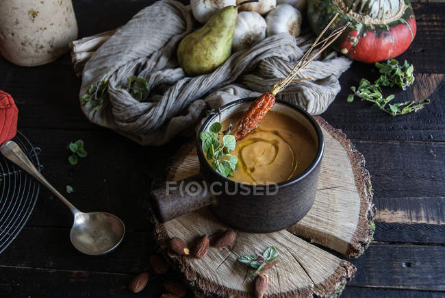 Sopa de crema de calabaza servida en un tazón de madera con ingredientes - foto de stock