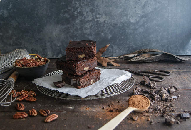 Pedaços de chocolate delicioso brownie o n rack de arame com ingredientes na superfície de madeira escura — Fotografia de Stock