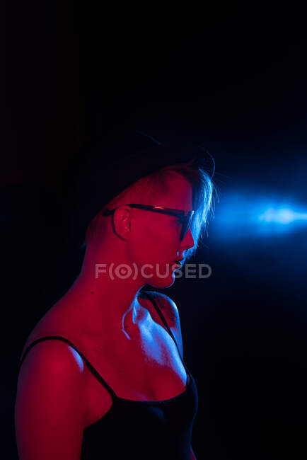 Привлекательная женщина с шляпной съемкой в студии с синим и красным огнями — стоковое фото