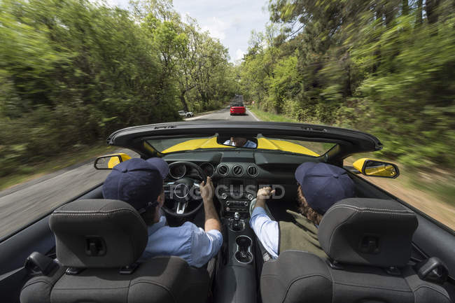 Homens dirigindo em carro rápido moderno na estrada no campo — Fotografia de Stock