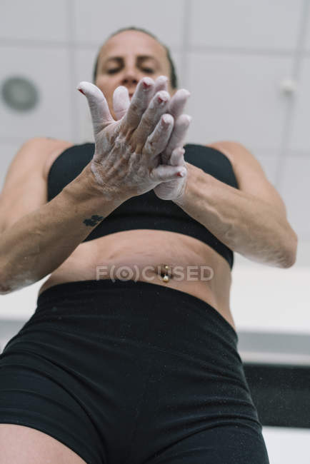 Woman spreading chalk on hands while training in gym — Stock Photo