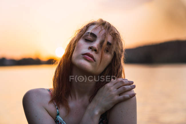 Sinnliche Frau mit geschlossenen Augen bei Sonnenuntergang in der Natur stehend — Stockfoto