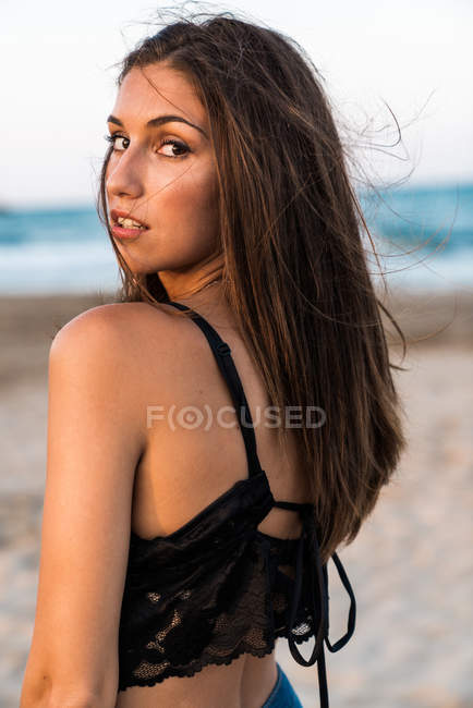 Splendida donna bruna in top nero in posa sulla spiaggia — Foto stock