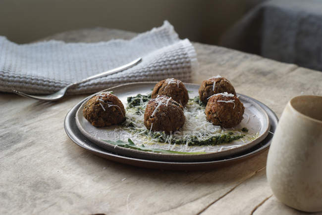 Lentil meatballs garnished with arugula pesto sauce and cheese on plate on wooden table — Stock Photo