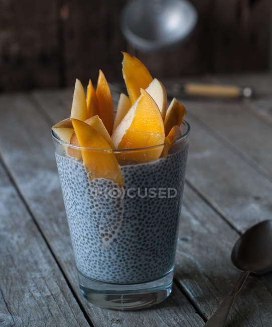 Смачний чіа пудинг з манго в склянці на дерев'яному столі — стокове фото