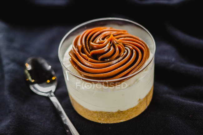 Dessert in cup with caramel mousse on black fabric — Stock Photo