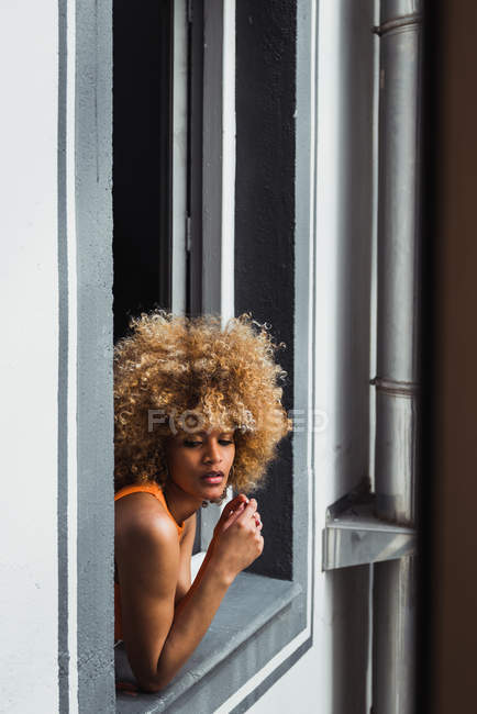 Curly ethnique femme regardant par la fenêtre — Photo de stock