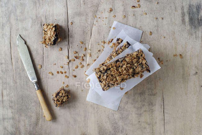 Barres de granola empilées maison sur le parchemin de cuisson sur la surface en bois — Photo de stock