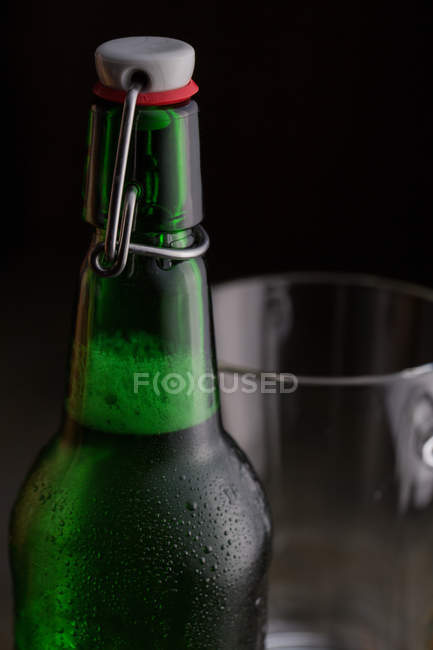Gros plan de bouteille de bière froide sur fond sombre — Photo de stock