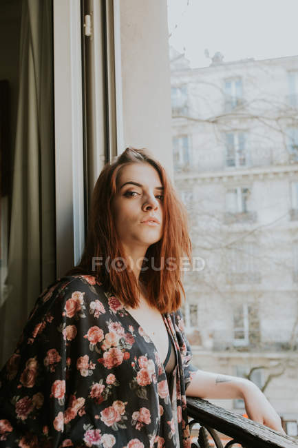 Retrato de Jovem mulher de pé na janela da cidade — Fotografia de Stock