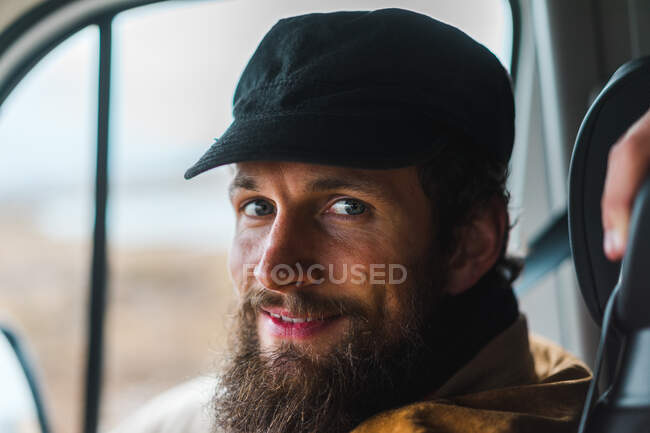 Нахабний бородатий чоловік усміхається і дивиться на камеру, подорожуючи Ісландією в машині.. — стокове фото