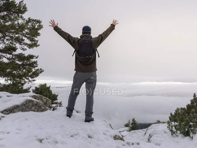 Wanderer und sein Hund blicken in die verschneiten Berge bei nebligem Himmel. — Stockfoto