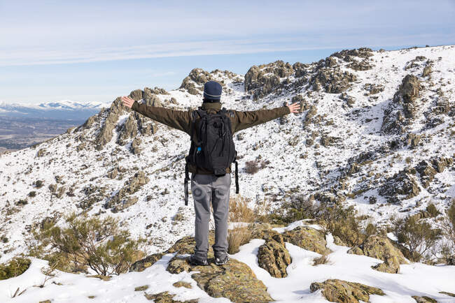 Young man with a backpack hiking enjoying in the snowy mountains on a winter sunny day. — Stock Photo