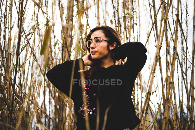 Mysterious girl in black outfit standing in dried grass — Stock Photo