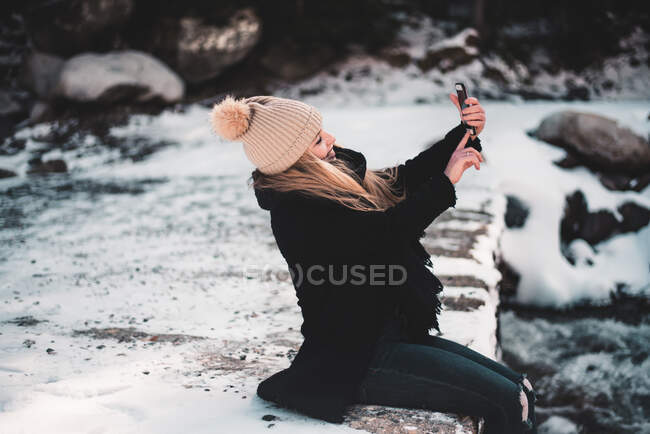 Frau macht Selfie am Fluss im Winter — Stockfoto