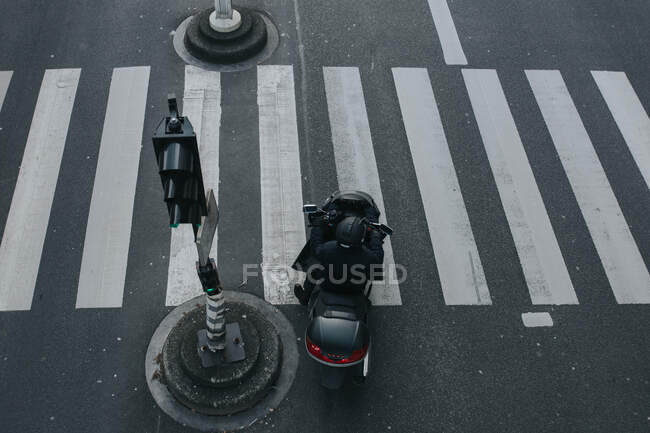 Desde arriba persona irreconocible a caballo scooter en el paso de peatones en París, Francia. - foto de stock