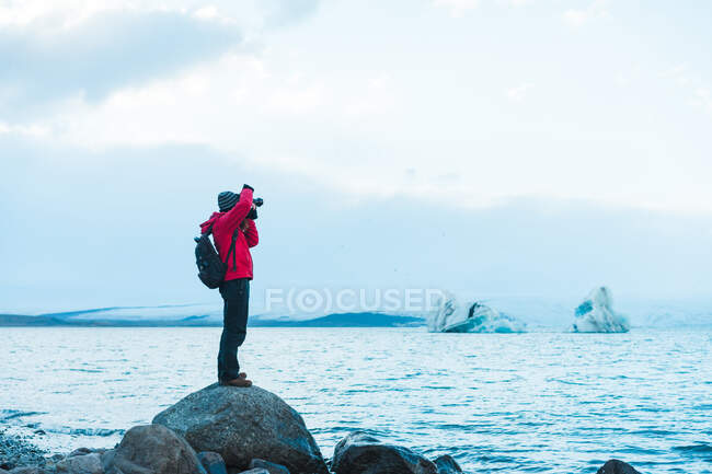 Homem em roupas quentes tirando fotos do lago — Fotografia de Stock