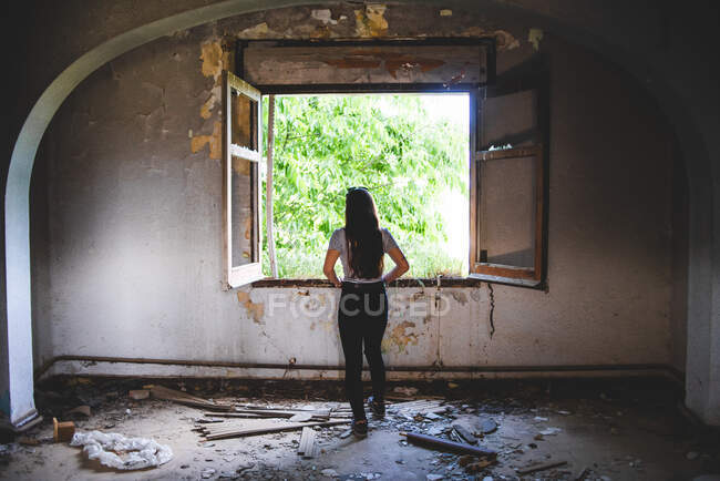 Silhueta de jovem mulher em pé perto de bela janela no edifício antigo — Fotografia de Stock