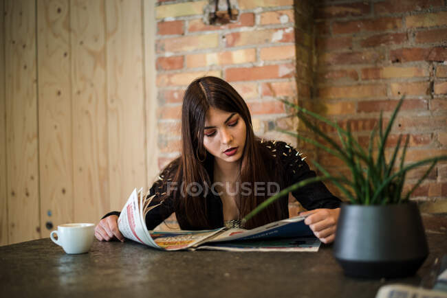 Giovane donna che legge giornale in caffè — Foto stock